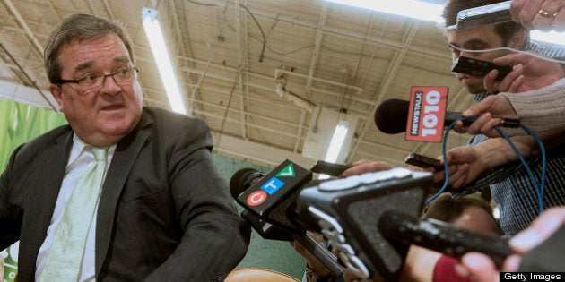 Jim Flaherty, Canada's finance minister, center, speaks to the media while trying on shoes to purchase, a pre-budget tradition, at the Roots Ltd. manufacturing facility in Toronto, Ontario, Canada, on Wednesday, March 20, 2013. Flaherty said his budget tomorrow will seek to balance the need for sound government finances with growth-promoting steps, including measures to help the nation?s manufacturers. Photographer: Norm Betts/Bloomberg via Getty Images