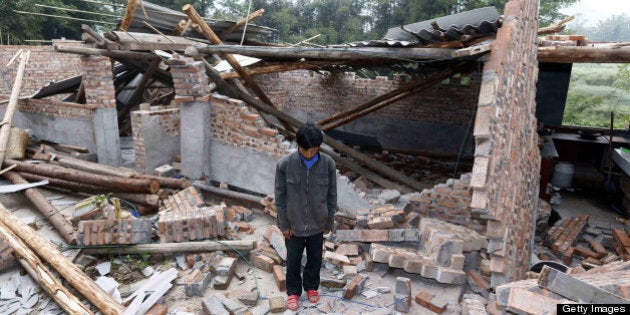 A local resident stands in ruins as he mourns in Lingguan township of Baoxing county in Yaan, southwest China's Sichuan province on April 27, 2013. China's southwestern Sichuan province stopped on April 27 to mourn the victims of a deadly earthquake that struck exactly a week ago, state media reported. CHINA OUT AFP PHOTO (Photo credit should read STR/AFP/Getty Images)