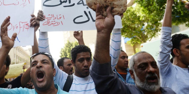 An Egyptian protester holds bread as fellow demonstrators shout slogans during a rally in downtown Cairo against the visit of a delegation from the International Monetary Fund (IMF) on April 3, 2013. An IMF delegation is in Cairo for talks on a financing programme needed to lift Egypt's economy out of crisis. The government has been walking a tight rope, as the reforms required by the international lender are likely to spark social tensions. AFP PHOTO / KHALED DESOUKI (Photo credit should read KHALED DESOUKI/AFP/Getty Images)