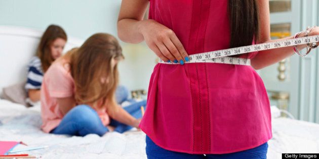 Teenage girl measuring her waist