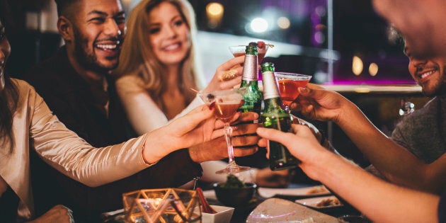 Group of friends clinking glasses while enjoying an evening meal in a restaurant on New Years Eve.