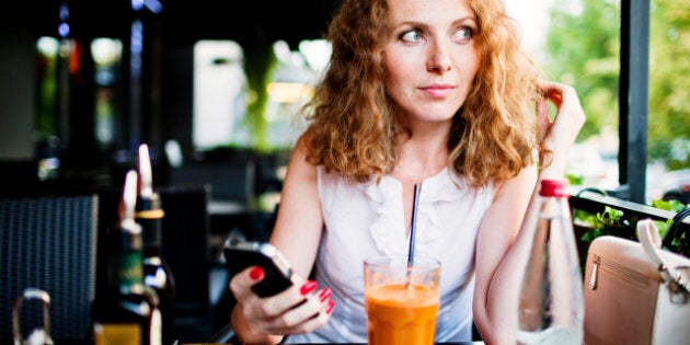 Woman with mobile phone waiting for order in a restaurant