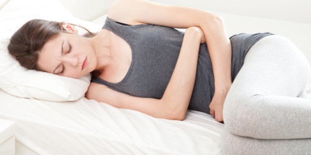 young woman in pain lying on bed