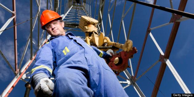 A royalty free image from the oil industry of an oil worker at a oil well.