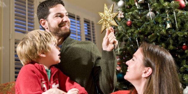 Family with child by Christmas tree, dad holding star