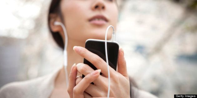 woman listening to music outside by smart phone