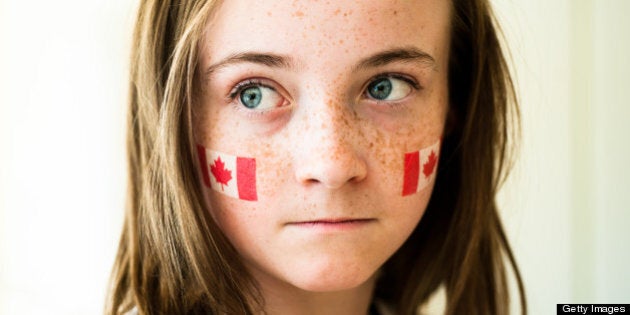 Girl with wide blue eyes and freckles, wearing Canadian flag on temporary tattoo on her cheeks.