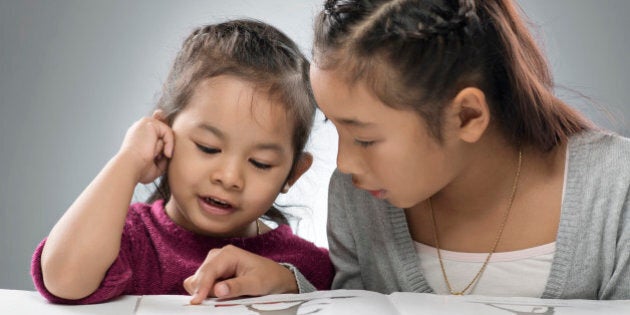 two sisters reading a picture book together