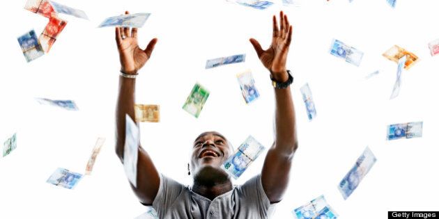 A happy man looks up smiling as he tries to catch hundreds of falling banknotes. The banknotes are varied denominations of the new South African currency featuring South African statesman, Nelson Mandela. Isolated on white.