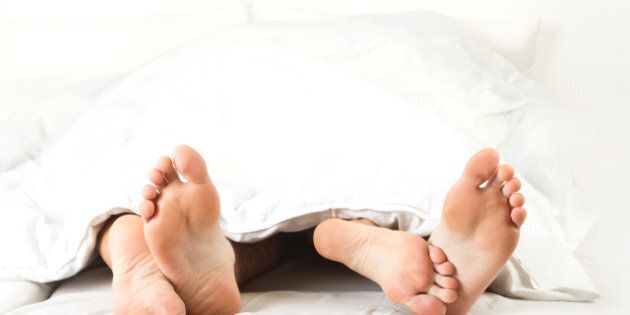 Foot of two people in the bedroom, on white background