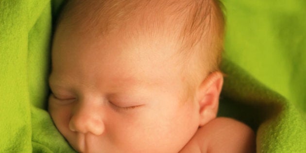 Newborn baby sleeping on a green blanket