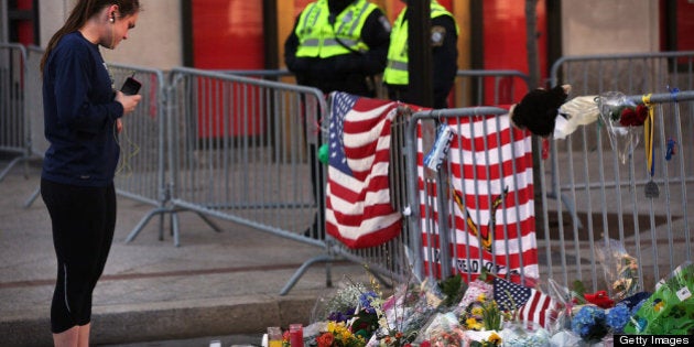 BOSTON, MA - APRIL 17: A woman looks at a street memorial near the scene of twin bombings at the Boston Marathon on April 17, 2013 in Boston, Massachusetts. The explosions, which occurred near the finish line of the 116-year-old Boston race on April 15, resulted in the deaths of three people with more than 170 others injured. Security has been heightened across the nation as the search continues for the person or people behind the bombings. (Photo by Spencer Platt/Getty Images)