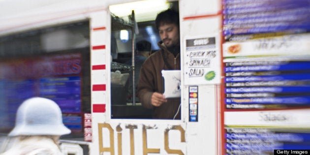 This March 28, 2013 photo illustration shot with a perspective control lens shows a customer purchasing lunch from one of the hundreds of vending trucks that set up shop along the streets of Washington, DC. Variety is the spice of life and foods from all around the globe can be found on the specialty food trucks. The AFP PHOTO/Paul J. Richards (Photo credit should read PAUL J. RICHARDS/AFP/Getty Images)