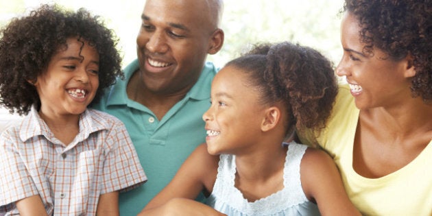 Young Family Relaxing On Sofa At Home