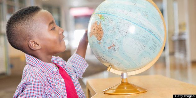 Excited little boy studying map in elementary school