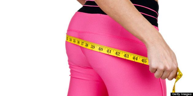 Woman wearing fitness clothing measuring her buttocks for a fitness and weight loss concept