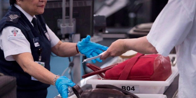 A CATSA employee performs security checks of passengers and their carry-on luggage at a screening area at Vancouver International Airport in Richmond, B.C. on Feb. 6, 2017.