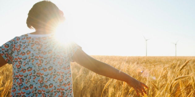 USA, Oregon, Wasco, Girl (10-11) walking in glorious sunshine amidst wheat