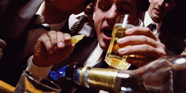 Businessmen having drinks at bar, man holding glass and slice of lime