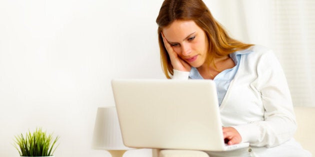 Portrait of a young boring woman working on laptop at home