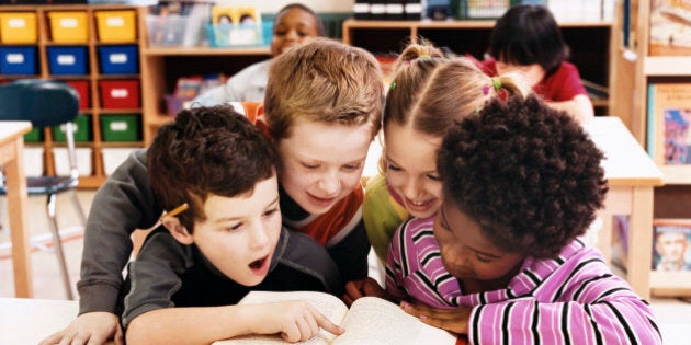 Girls and Boys Looking at the Same Textbook in a Classroom at Primary School