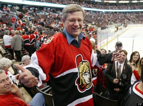 Canadian Prime Minister Stephen Harper autographs a fan's jersey