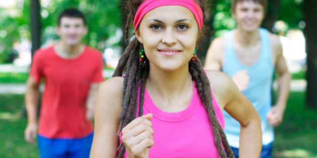 smiling girl jogging with two...