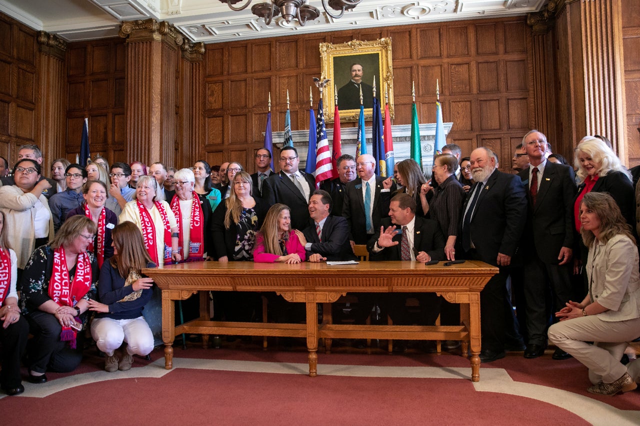 Democratic state Rep. Mary Caferro, left, and Republican state Rep. Ed Buttrey, right, just after Bullock (center) signed a bill to continue Montana's Medicaid expansion program on Thursday in Helena.