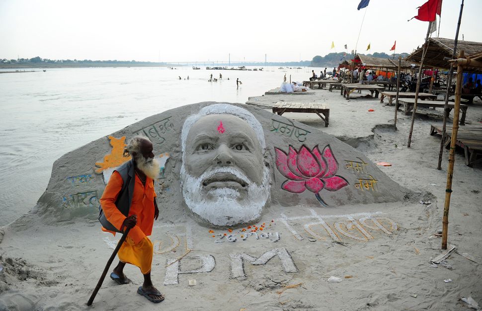 An sadhu walks past a sand sculpture of Prime Minister-designate Narendra Modi at the Sangam in Allahabad on May 26, 2014. 