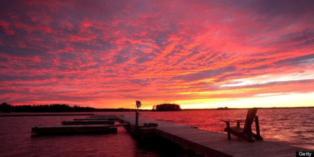 A beautiful sunset in the Muskoka region of Ontario. Dock with muskoka chair. Summer evening.