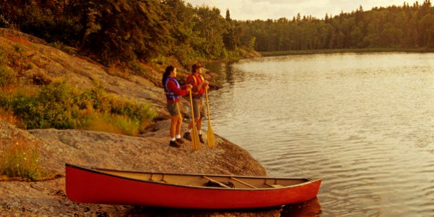 couple with canoe along Big Whiteshell Lake, Whiteshell Provincial Park, Manitoba, Canada