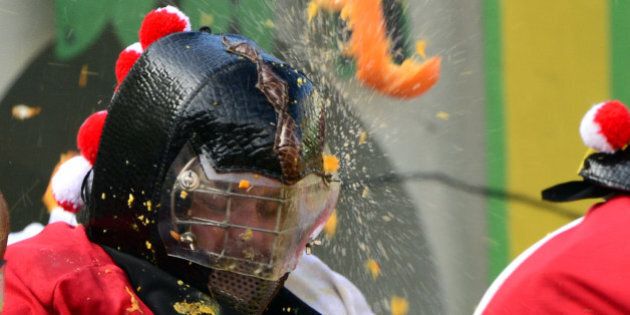 Men with helmets are hit by oranges during the traditional 'battle of the oranges' held during the carnival in Ivrea, near Turin, on March 4, 2014. During the event which marks the people's rebellion against tyrannical lords who ruled the town in the Middle Ages, revellers parading on floats represent guards of the tyrant, while those on foot the townsfolk. AFP PHOTO / GIUSEPPE CACACE (Photo credit should read GIUSEPPE CACACE/AFP/Getty Images)
