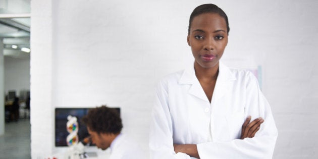 Portrait of a female biologist with her colleague working in the background