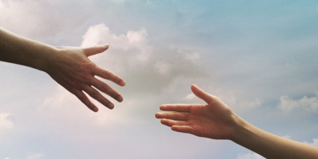 Hand of father and daughter seem to reach together in the sky