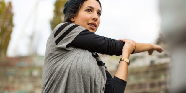 Sporty woman stretching arms before exercise outdoors