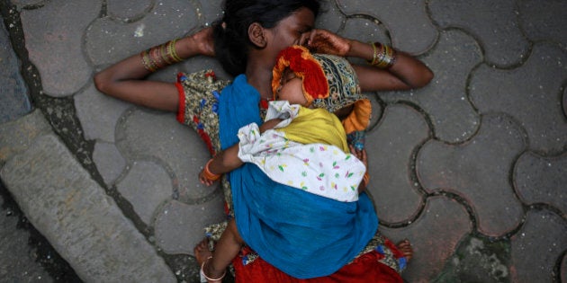 A woman sleeps with her baby on sidewalk at a market in Mumbai August 13, 2014. REUTERS/Danish Siddiqui (INDIA - Tags: SOCIETY)