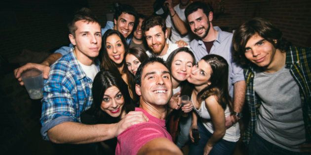 Smiling friends taking selfie in nightclub