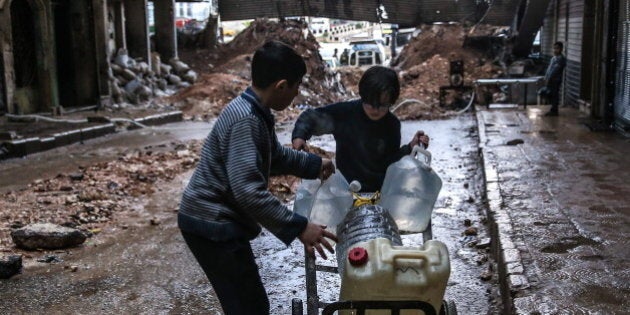 SYRIA. MARCH 5, 2016. Boys pull a trolley with containers of drinking water through a muddy street in Salah al-Din, Aleppo. Valery Sharifulin/TASS (Photo by Valery Sharifulin\TASS via Getty Images)