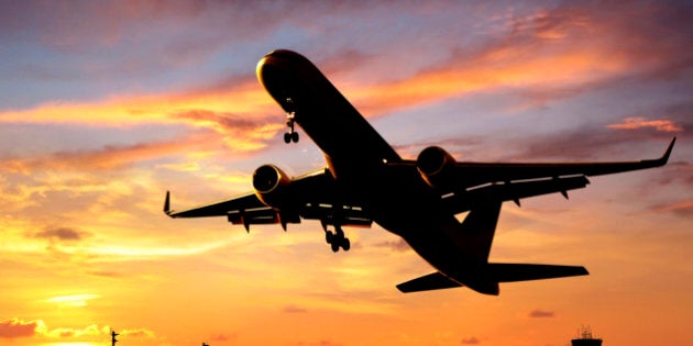 close up shot of airplane taking off over sunset.