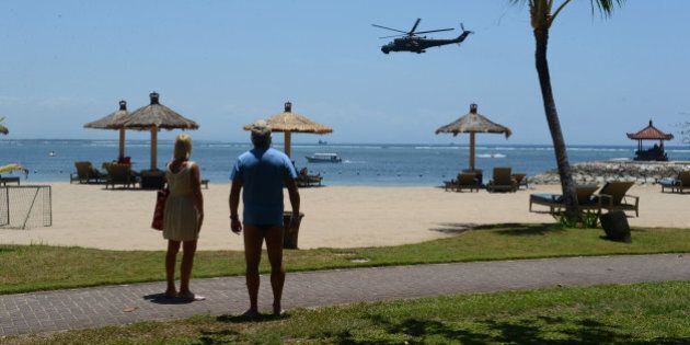 In this photograph taken on September 29, 2013, tourists watch Indonesian military helicopters patroling the beach area of Nusa Dua, close to the venue of the Asia-Pacific Economic Cooperation (APEC) summit in Indonesia's resort island of Bali. Indonesian authorities have increased security ahead of the APEC summit where 21 world leaders including US President Barack Obama will participate in the leaders summit from October 7 to 8. AFP PHOTO / ROMEO GACAD (Photo credit should read ROMEO GACAD/AFP/Getty Images)