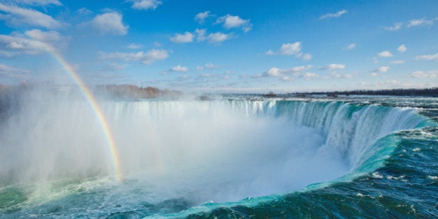 The Horseshoe Falls with a rainbow with scattered clouds in the sky.