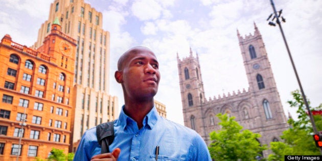 A young black businessman smiles with confidence as he goes to work in Old Montreal.