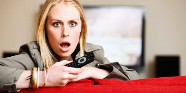 This cute young blonde woman holding a remote control seems utterly horrified by something she's seen on the television behind her. Shot with Canon EOS 1Ds Mark III.