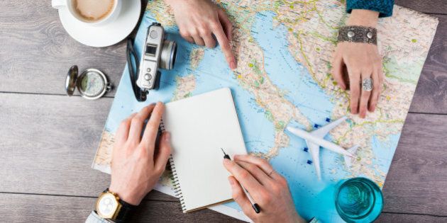 Two young people together planning trip to Europe. Top view. empty white space in notebook where you can place your text or advertisement. Romantic travel