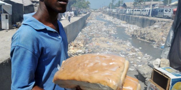 A man carries bread on April 11, 2013 close to a public garbage area in the south of Port-au-Prince. AFP Photo Thony BELIZAIRE (Photo credit should read THONY BELIZAIRE/AFP/Getty Images)