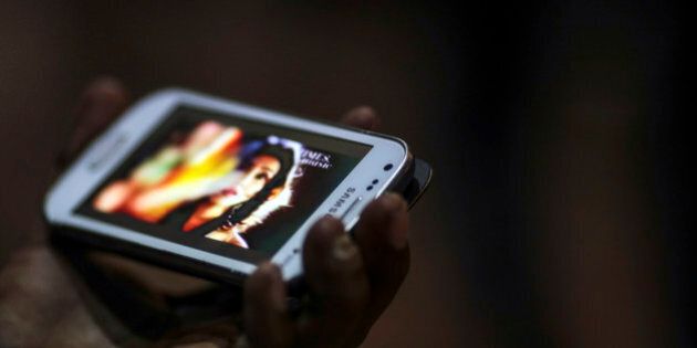 A man watches a video on a Samsung Electronics Co. smartphone in Mumbai, India, on Saturday, Feb. 28, 2015. The government auction of telecom wireless spectrum starting March 4 is expected to raise as much as $15.6 billion from service providers including those controlled by billionaires Kumar Mangalam Birla, Sunil Mittal and Anil Ambani, according to ICRA Ltd. Photographer: Dhiraj Singh/Bloomberg via Getty Images
