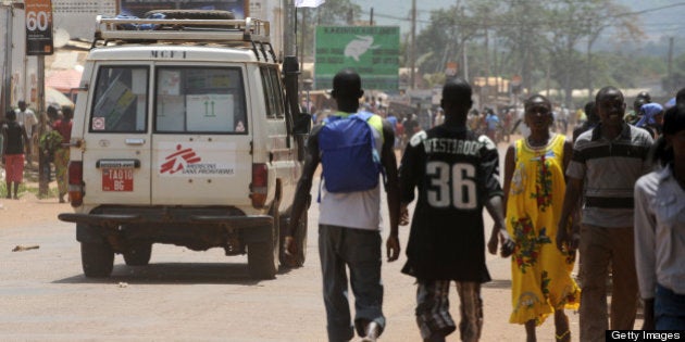 People walk a car with a flag of Medecins Sans Frontieres (MSF, Doctors without borders) in a street of Bangui, on March 28, 2013. New rebel authorities in the Central African Republic struggled to restore order in the coup-hit capital as the UN warned tens of thousands of people faced going hungry after days of looting. Drinking water and electrical power were still cut off in parts of Bangui after Michel Djotodia and his Seleka coalition seized the city on March 24, 2013, forcing president Francois Bozize to flee. AFP PHOTO / SIA KAMBOU (Photo credit should read SIA KAMBOU/AFP/Getty Images)