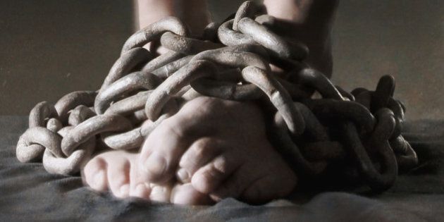 Close-up of bare feet bound in heavy metal chains