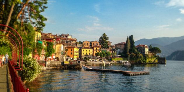 Panoramic view of Lake Como in Northern Italy and the beautiful midieval village of Varenna with people walking along the scenic walkway on the waters edge.A popular tourist destination.