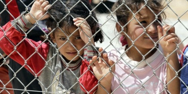 TO GO WITH AFP STORY BY KAMAL TAHA - Syrian refugee children, who fled the deadly conflict in their country, look through a fence on April 28, 2015 at Azraq refugee camp in Jordan, some 100 kilometres (60 miles) east of Amman. The camp, which opened a year ago, has now a population of 18,000 and a capacity of 100,000. AFP PHOTO / KHALIL MAZRAAWI (Photo credit should read KHALIL MAZRAAWI/AFP/Getty Images)